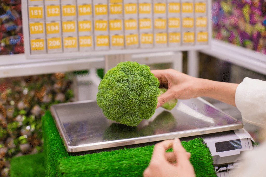 Etiquetage alimentaire : 5 conseils pour assurer sa fiabilité Balance fruits et légumes avec une main de femme déposant un brocolis