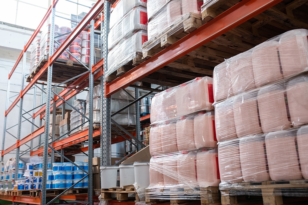 Lean logistics : en quoi cette méthode peut-elle sauver votre organisation logistique en période de fêtes ? Bidons recouverts de film étirable placés sur des palettes dans la salle de stockage, cadre métallique avec articles